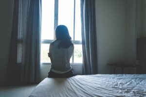 A woman sitting on the bed. She has abandonment trauma.