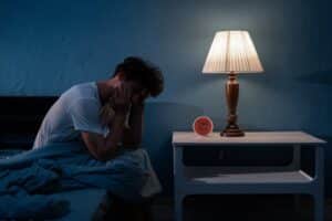 A man sitting on the bed and experiencing sleep anxiety